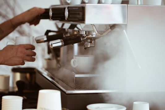 person holding white mug brewing coffee