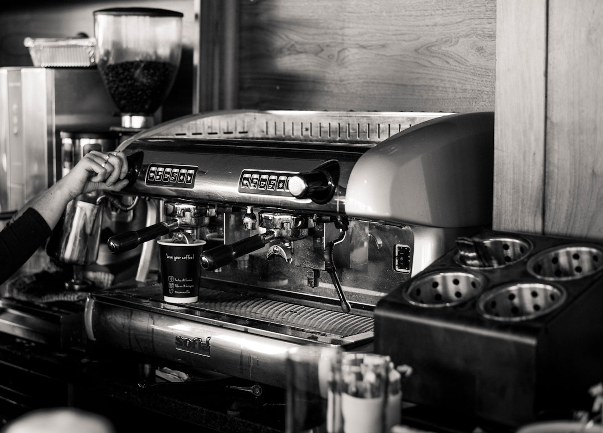 grayscale photography of person using espresso machine