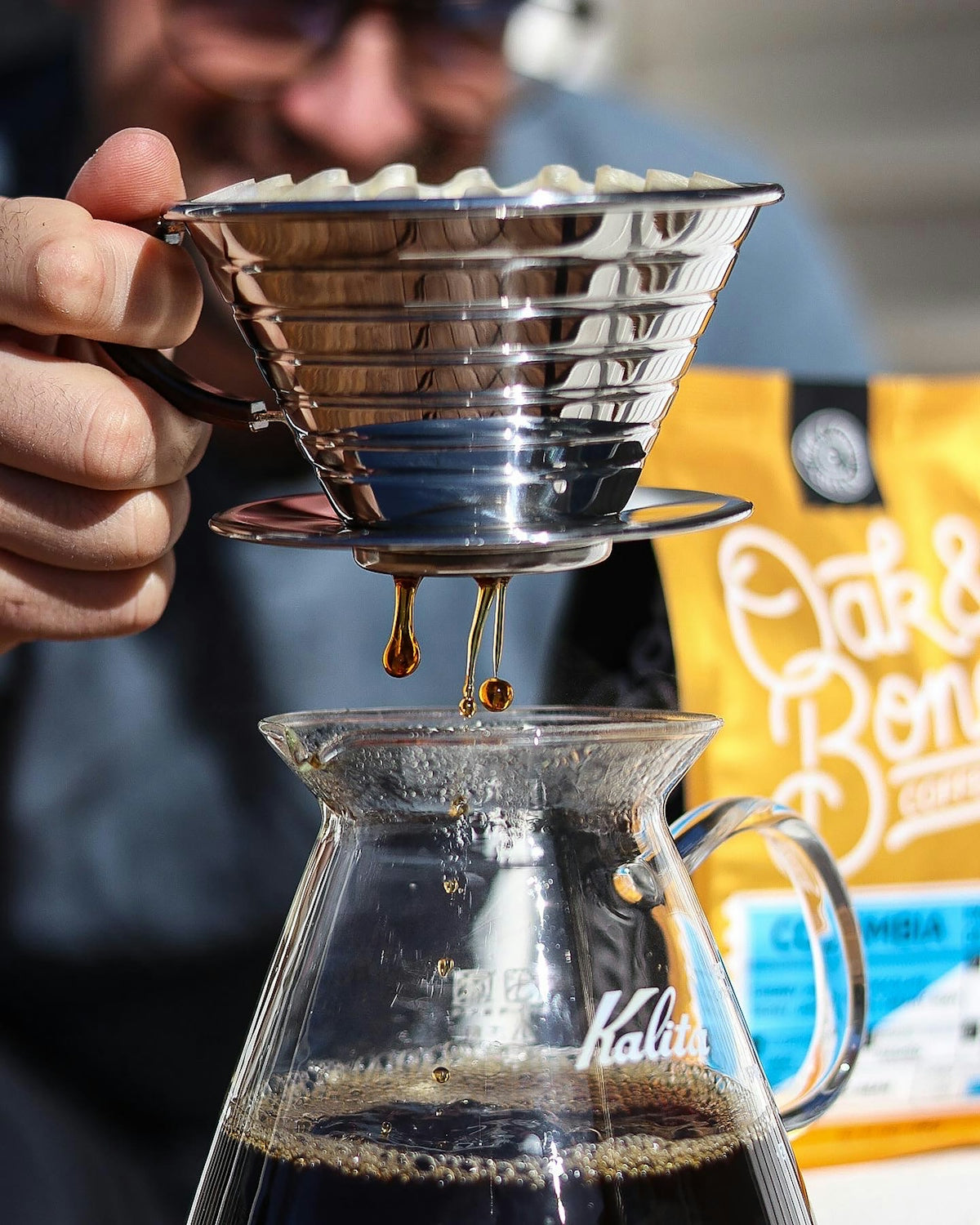 a person pours coffee into a glass pitcher