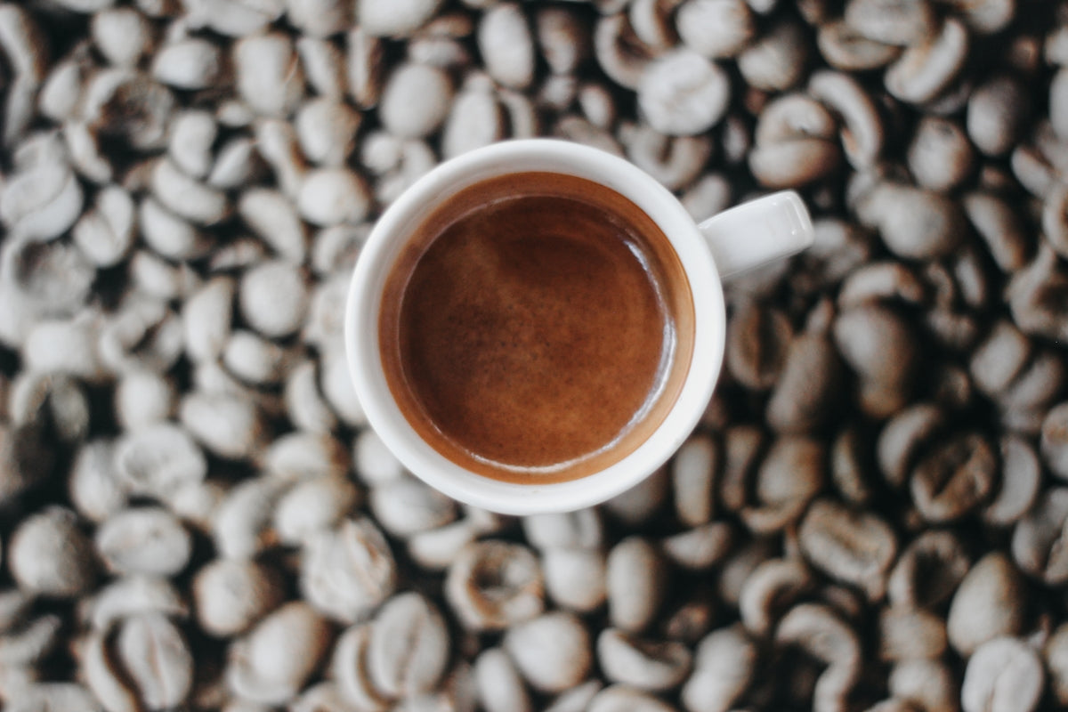 a cup of coffee sitting on top of a pile of coffee beans
