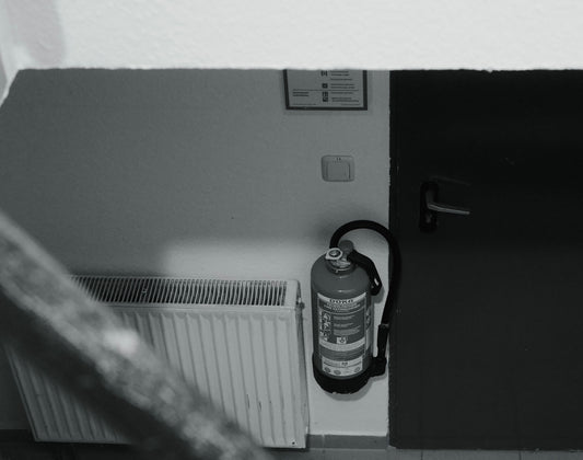 Fire extinguisher mounted on wall next to radiator.