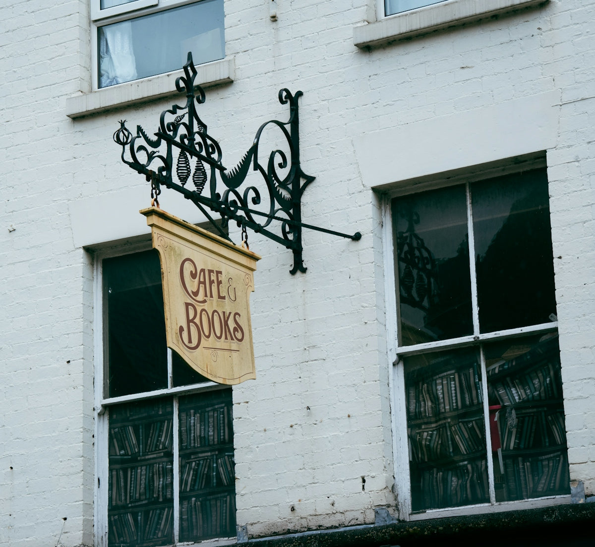 A hanging sign reading Cafe & Books on a white brick building